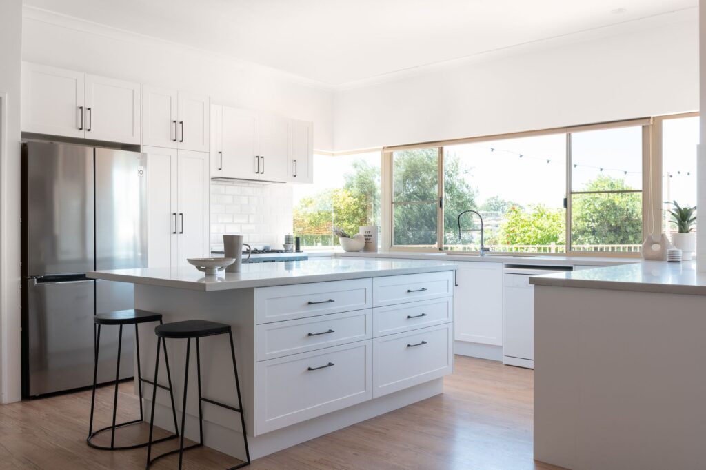 Large open plan kitchen , with white cabinets and black hardware.