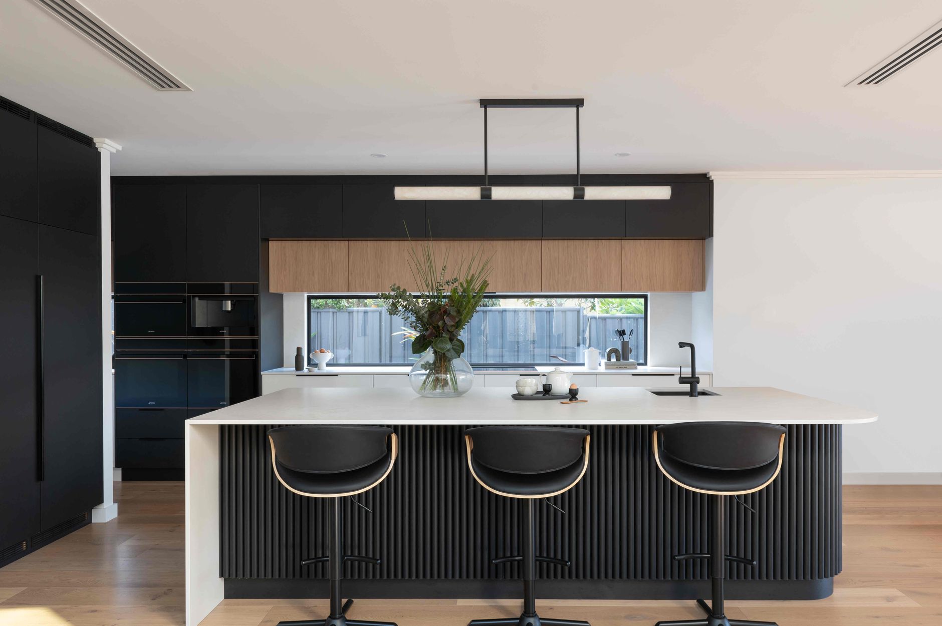 Modern monochrome kitchen with natural accents and a glass window splashback