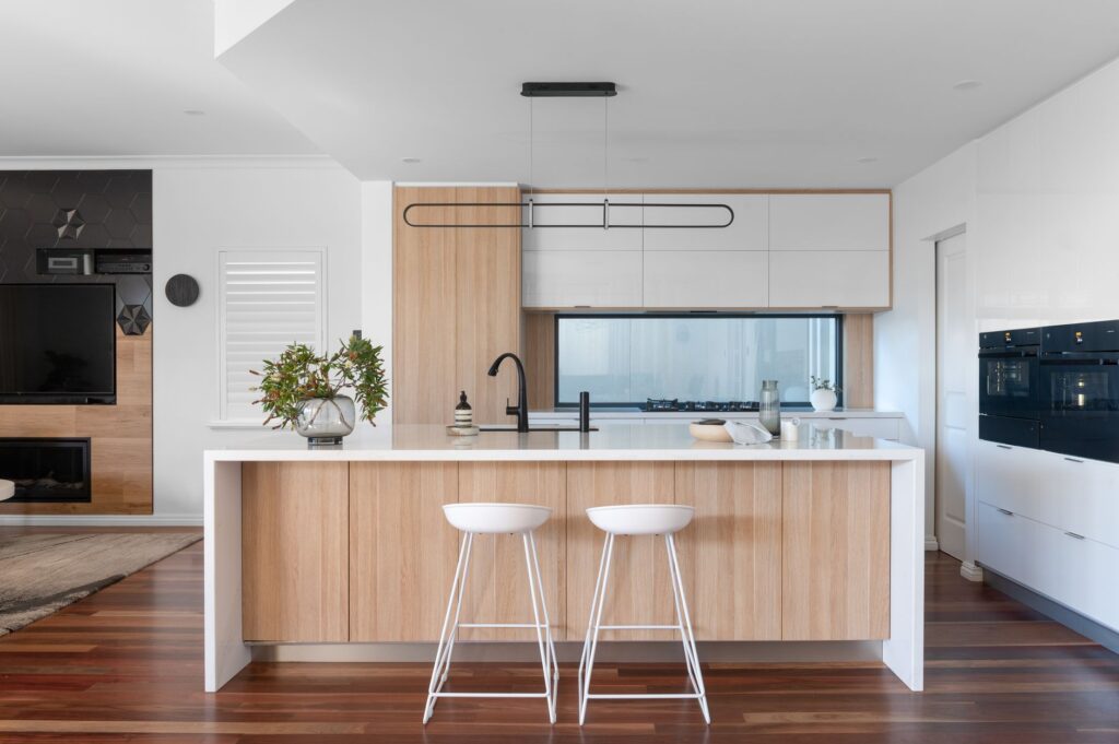 Large open plan kitchen with glass window splashback and natural accents