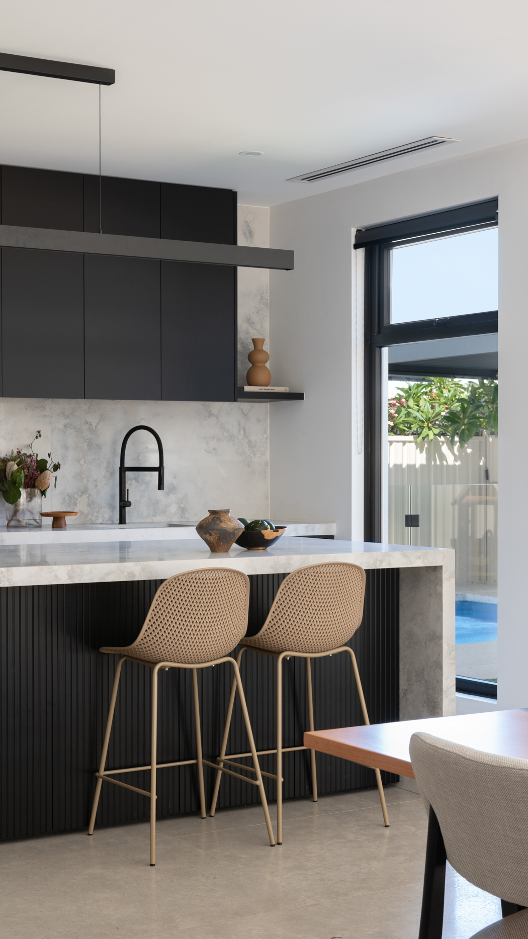 Stone island and full height stone splashback with matte black tapware in a Perth kitchen